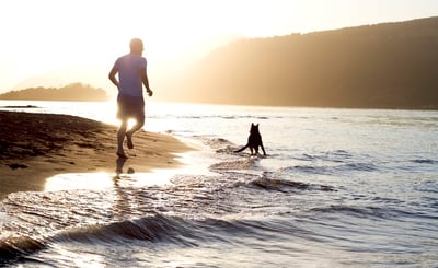Man running on the beach with a dog