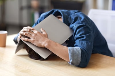 worker hiding under laptop