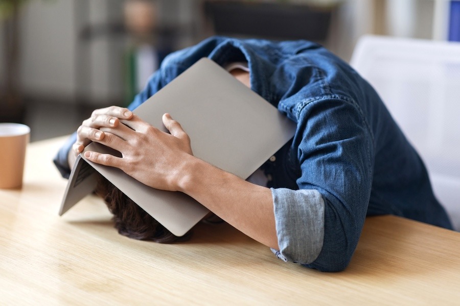 worker hiding under laptop